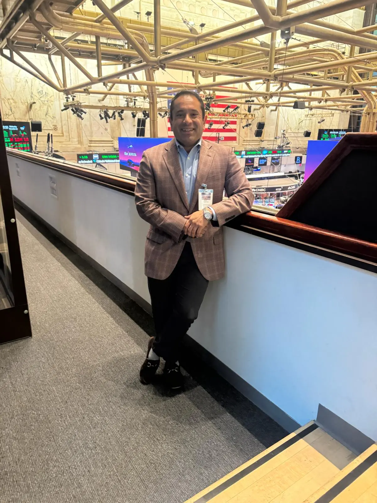 Nik Agharkar leaning on the rail above the New York Stock Exchange trading floor