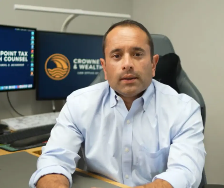 Nik Agharkar at his desk, with the Crowne Point Tax & Wealth Counsel logo on the screen behind him