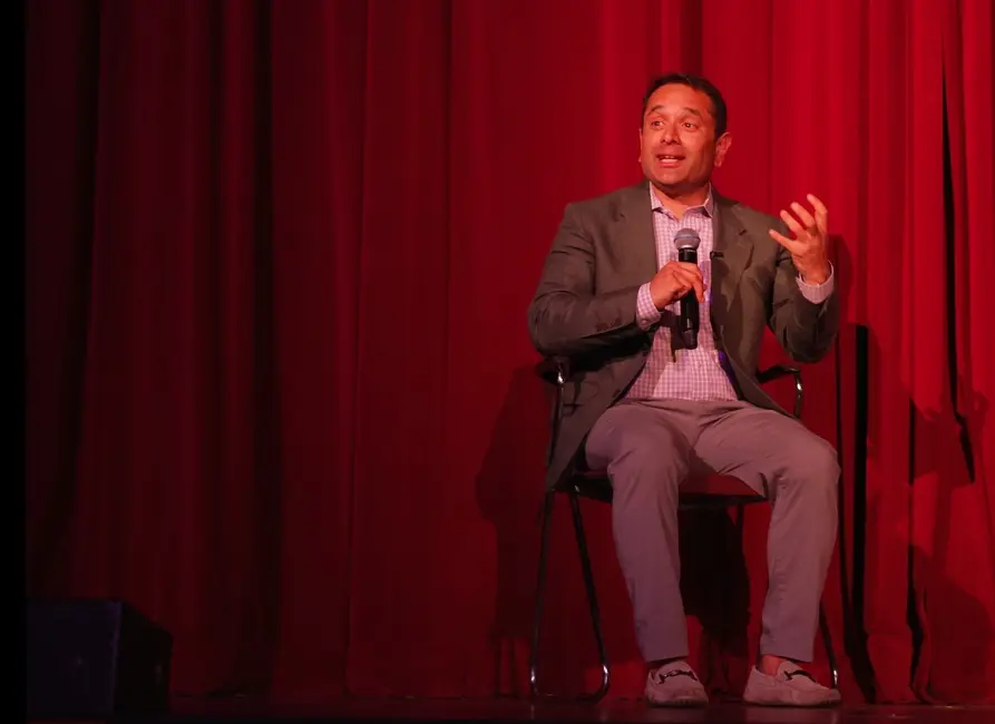 Nik Agharkar seated on stage, answering a question with a microphone