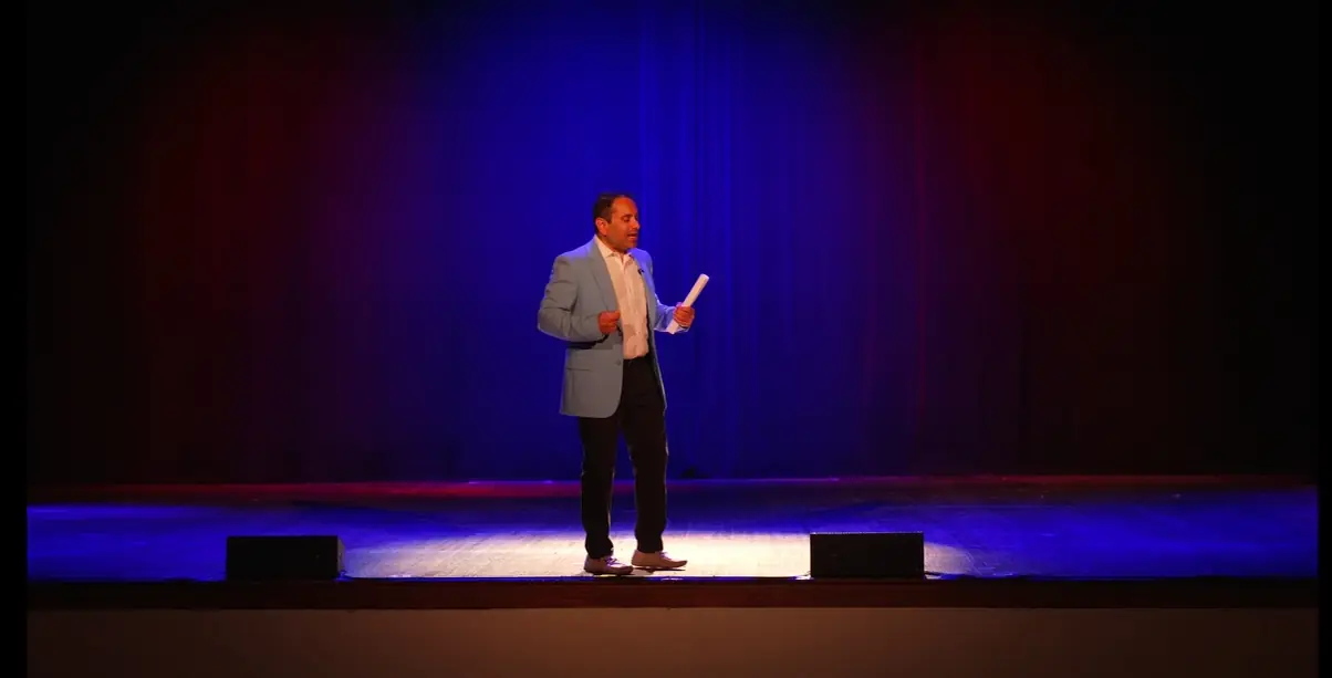 Nik Agharkar presenting on stage with notes in hand